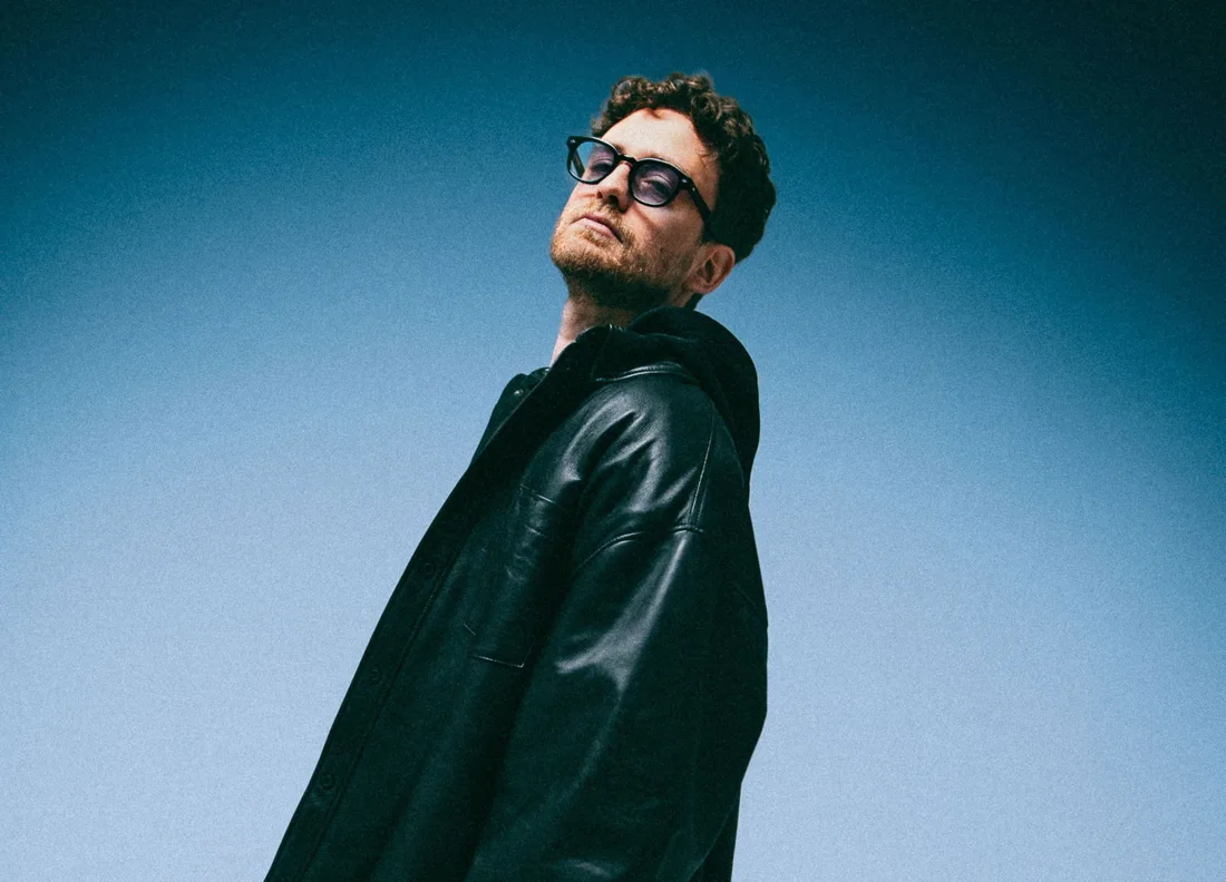 Franky Rizardo in sunglasses and a dark jacket against a blue background
