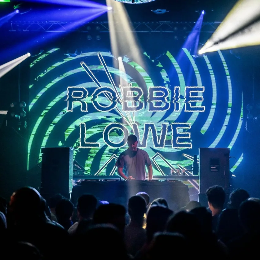Robbie Lowe performing beneath a screen displaying his name