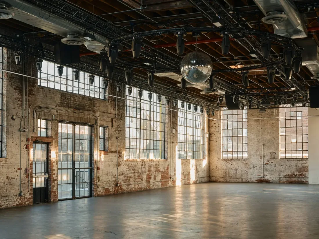 99 Scott Ave empty brick main room with steel windows and disco ball