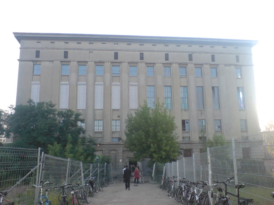 Berghain power-station facade from the entrance path, bikes along the fence