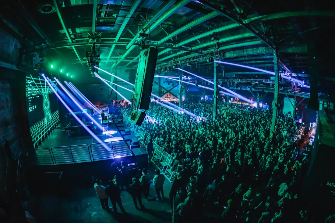 Brooklyn Pacha packed warehouse dancefloor under steel trusses and lasers