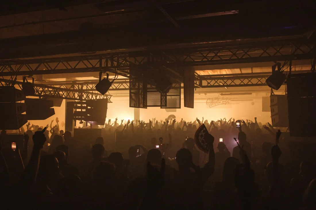 Crowd surrounding a DJ booth inside Drumsheds