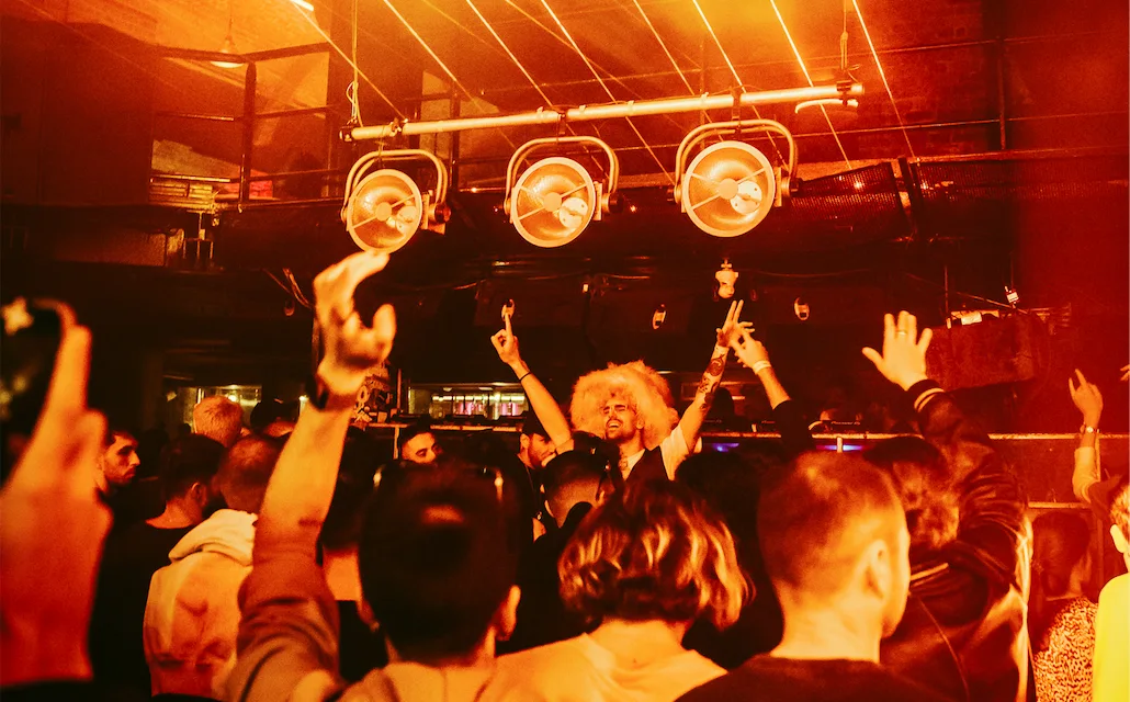 DJ and dancing crowd under orange lights at fabric, from its official 23rd birthday retrospective