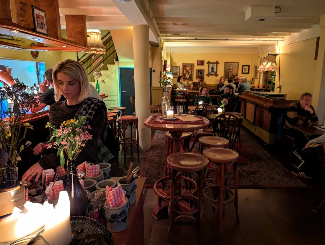 Het Dorp candlelit bar room with stools, rugs, framed paintings and guests