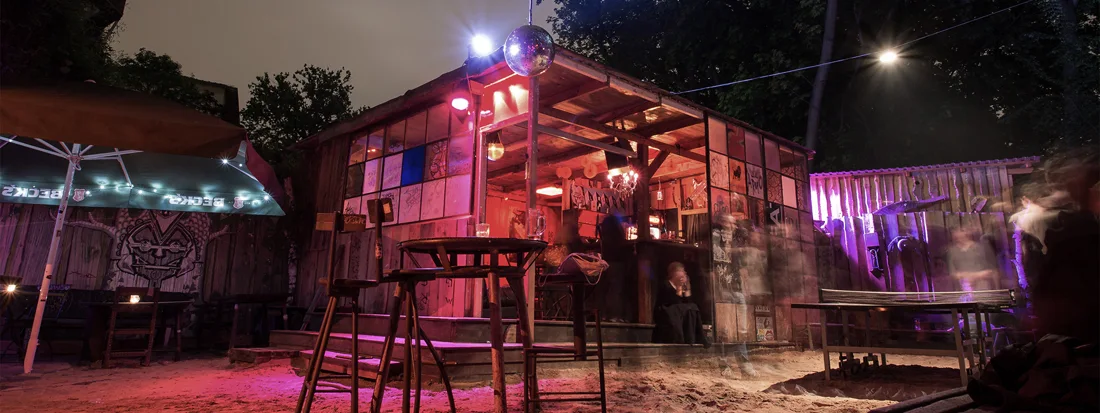 Humboldthain Club sandy garden with wooden bar hut and disco ball