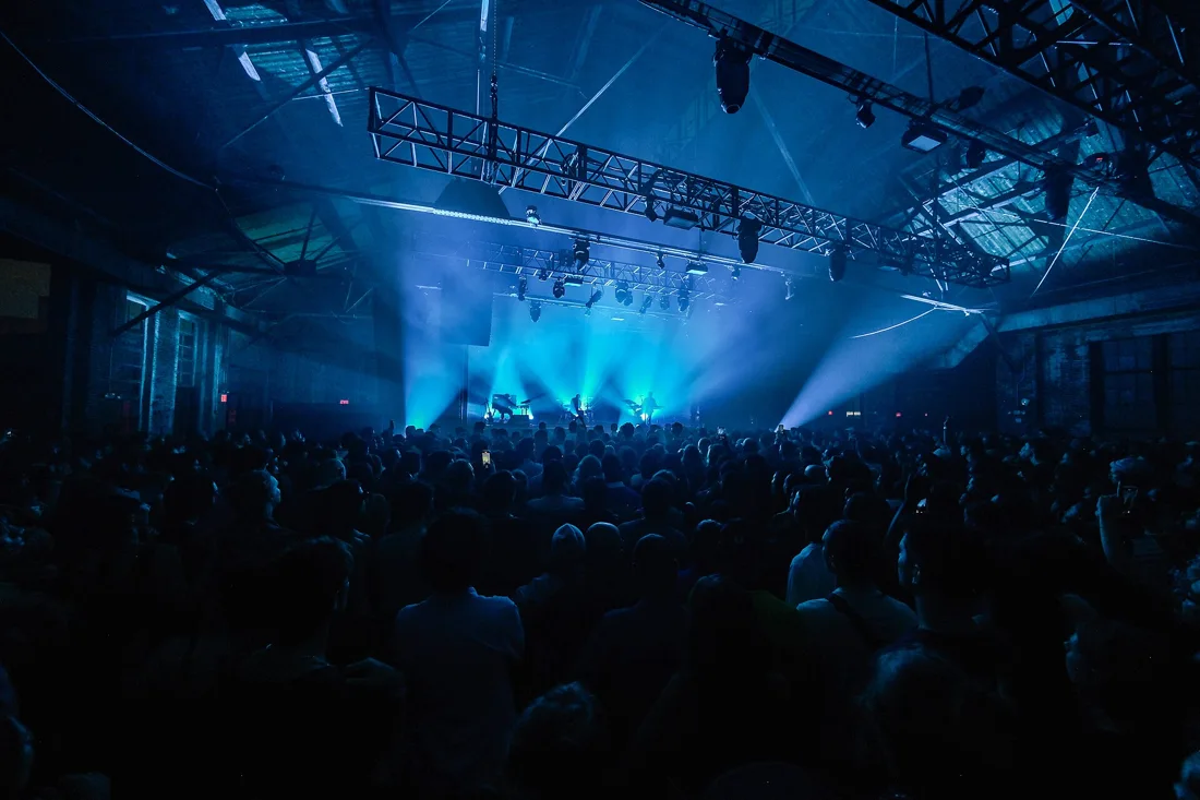 Knockdown Center main hall, blue-lit stage, truss rig and crowd