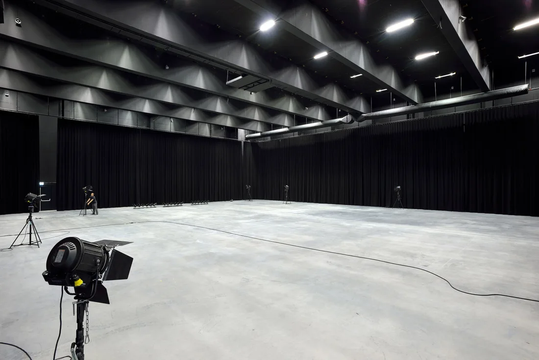 Mediahaven empty black-walled studio hall with film lights and concrete floor