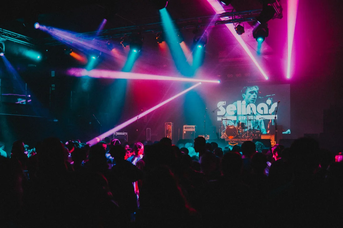 Selina's stage under coloured beams, crowd, Selina's name on the screen