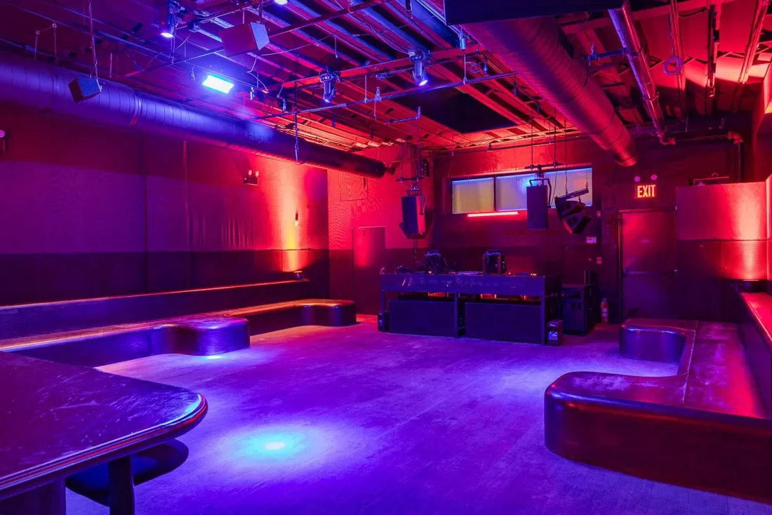 Signal empty dancefloor with DJ booth and bench seating, red-purple light