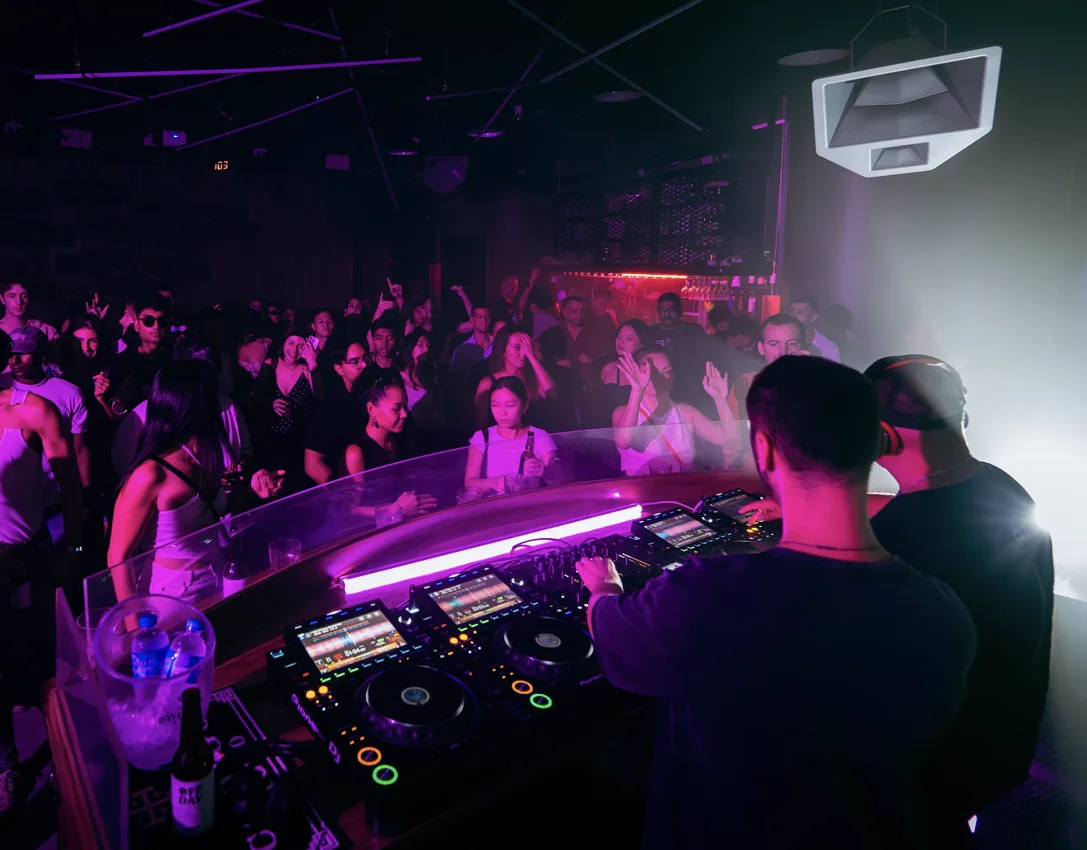DJs performing behind a booth with a club-night crowd at TUFF Club Singapore